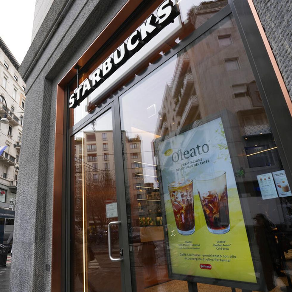 Un letrero que anuncia el café Oleato se destaca en el frente de una cafetería de la cadena Starbucks en Milán, Italia, el lunes 27 de febrero de 2023. Añadir aceite de oliva al café no es una tradición en Italia, pero eso no impidió que Howard Schultz, director general interino de Starbucks, lanzara una serie de bebidas que combinan ambos ingredientes y que actualmente se ofrecen en Milán, la ciudad que inspiró su imperio de cafeterías. (AP Foto/Antonio Calanni)