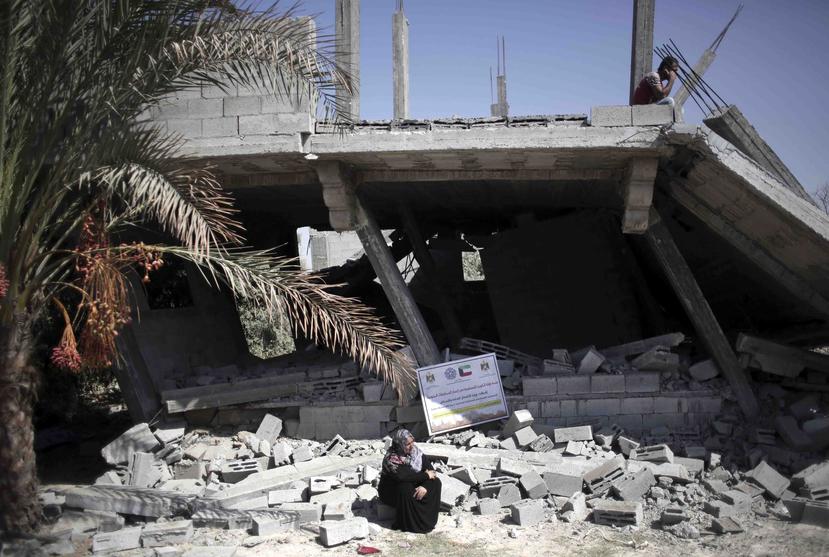 Una mujer sentada frente a una casa destruida por el ataque israelí. (AP)