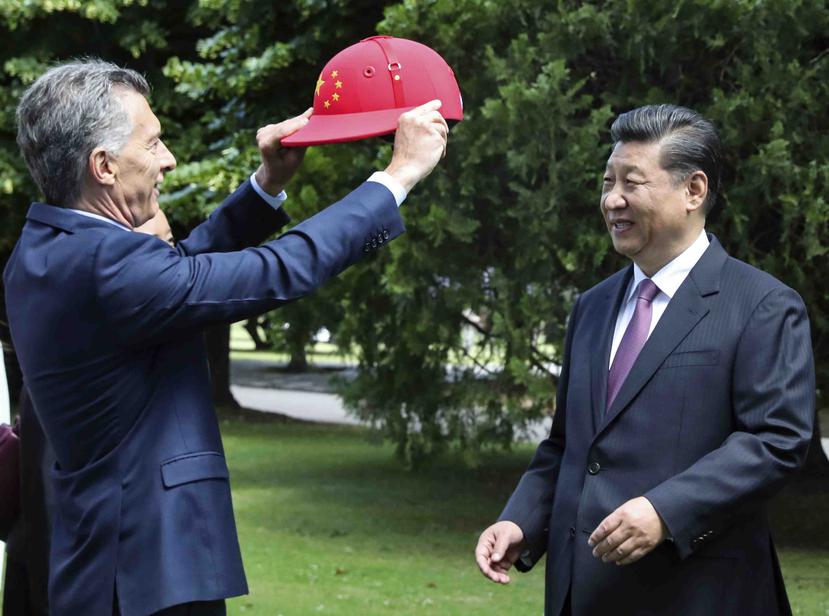 El mandatario chino Xi Jinping recibe un casco de polo decorado con la bandera de China de parte del presidente argentino Mauricio Macri. (AP)
