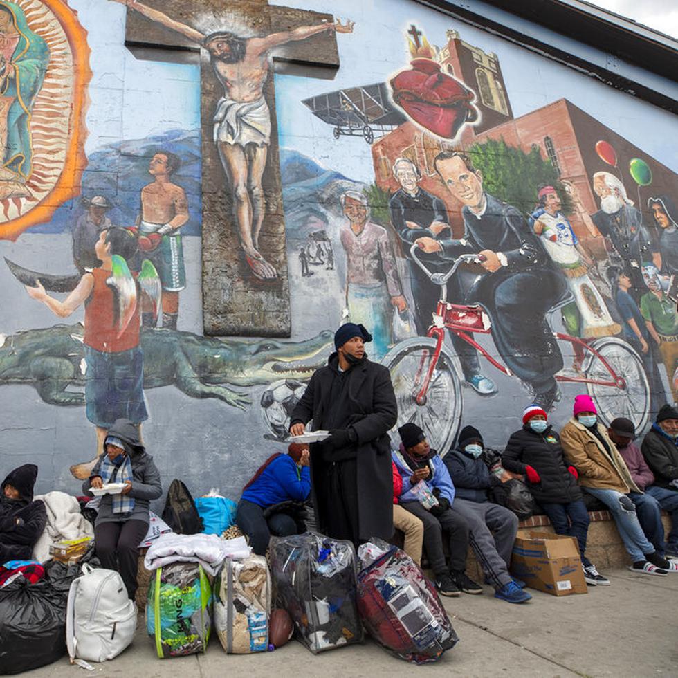 Migrantes comen y esperan ayuda, acampados en una calle del centro de El Paso, Texas, 18 de diciembre de 2022.  (AP Foto)