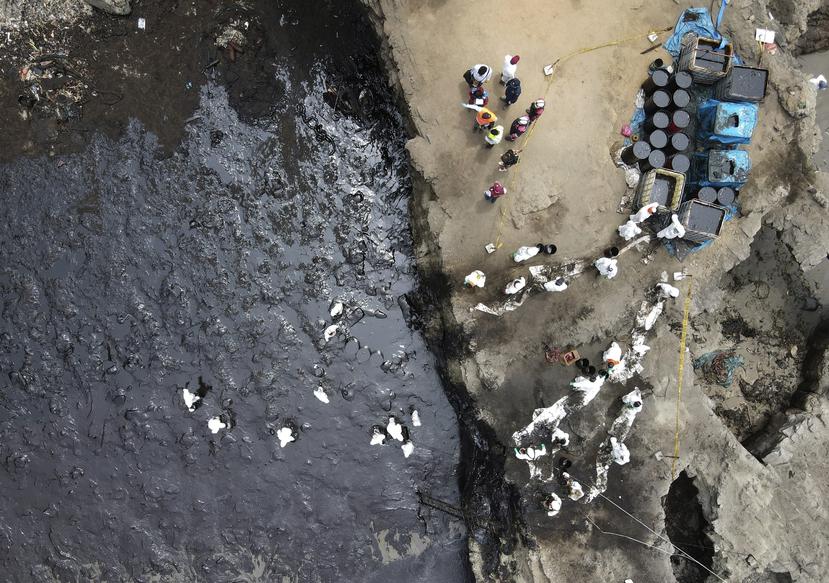 Los trabajadores continúan en una campaña de limpieza después de un derrame de petróleo, en Playa Cavero en el distrito de Ventanilla de Callao, Perú.