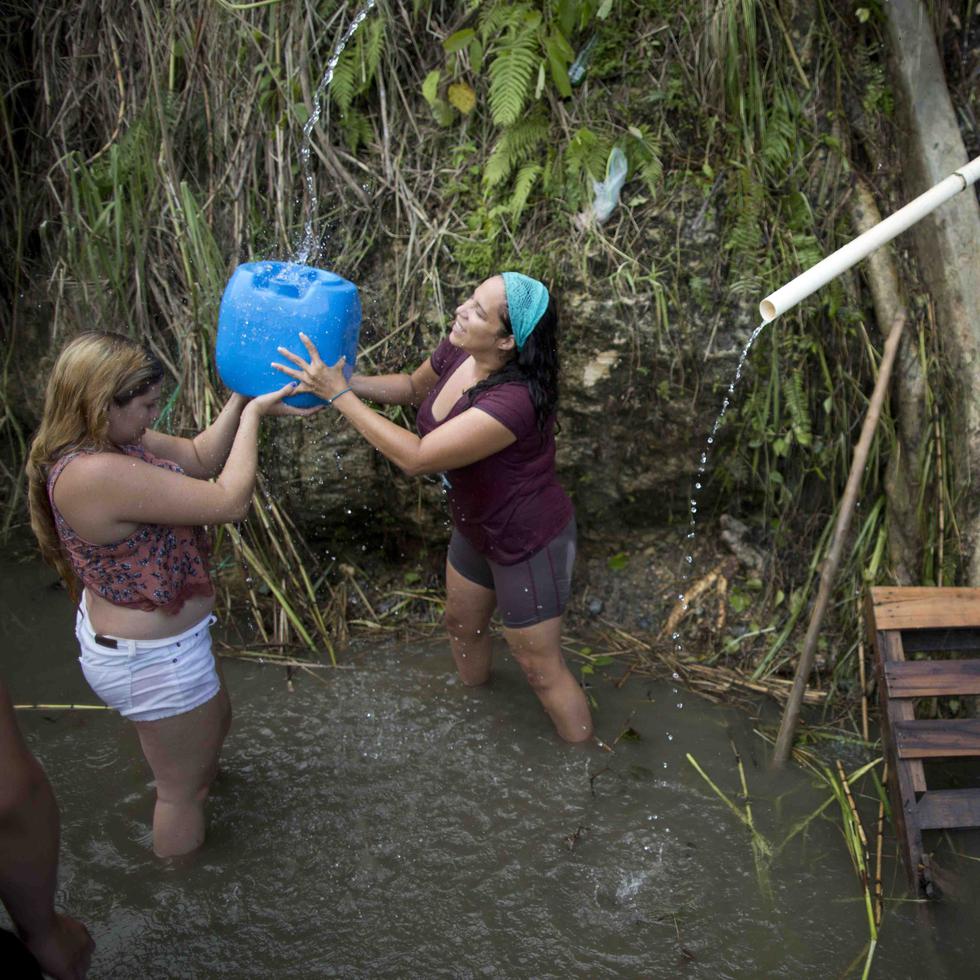 Un grupo de ciudadanos llena sus envases de agua en un manantial en Corozal.