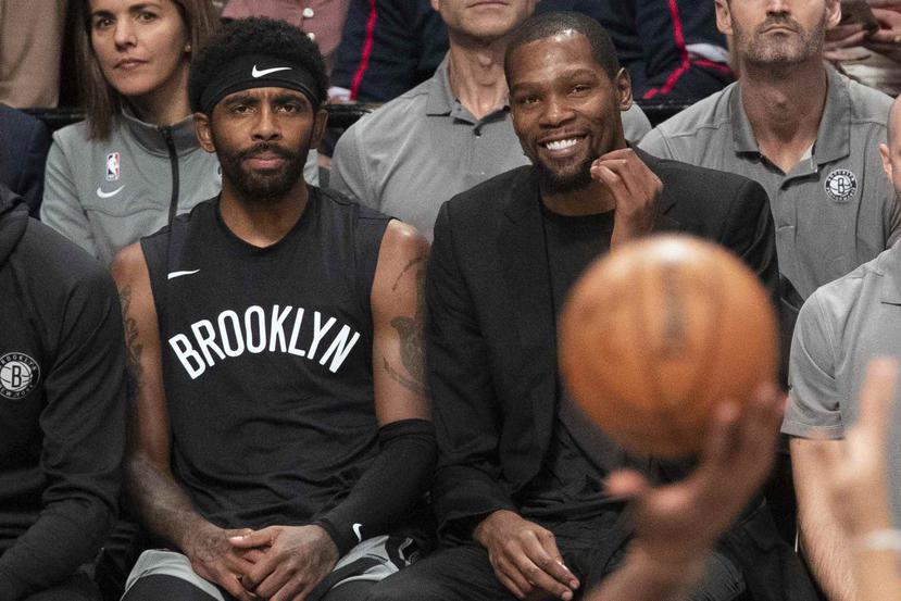 En esta foto del 1 de noviembre de 2019, Kyrie Irving (izquierda) y Kevin Durant de los Nets de Brooklyn observan un partido contra los Rockets de Houston en Nueva York. (AP)