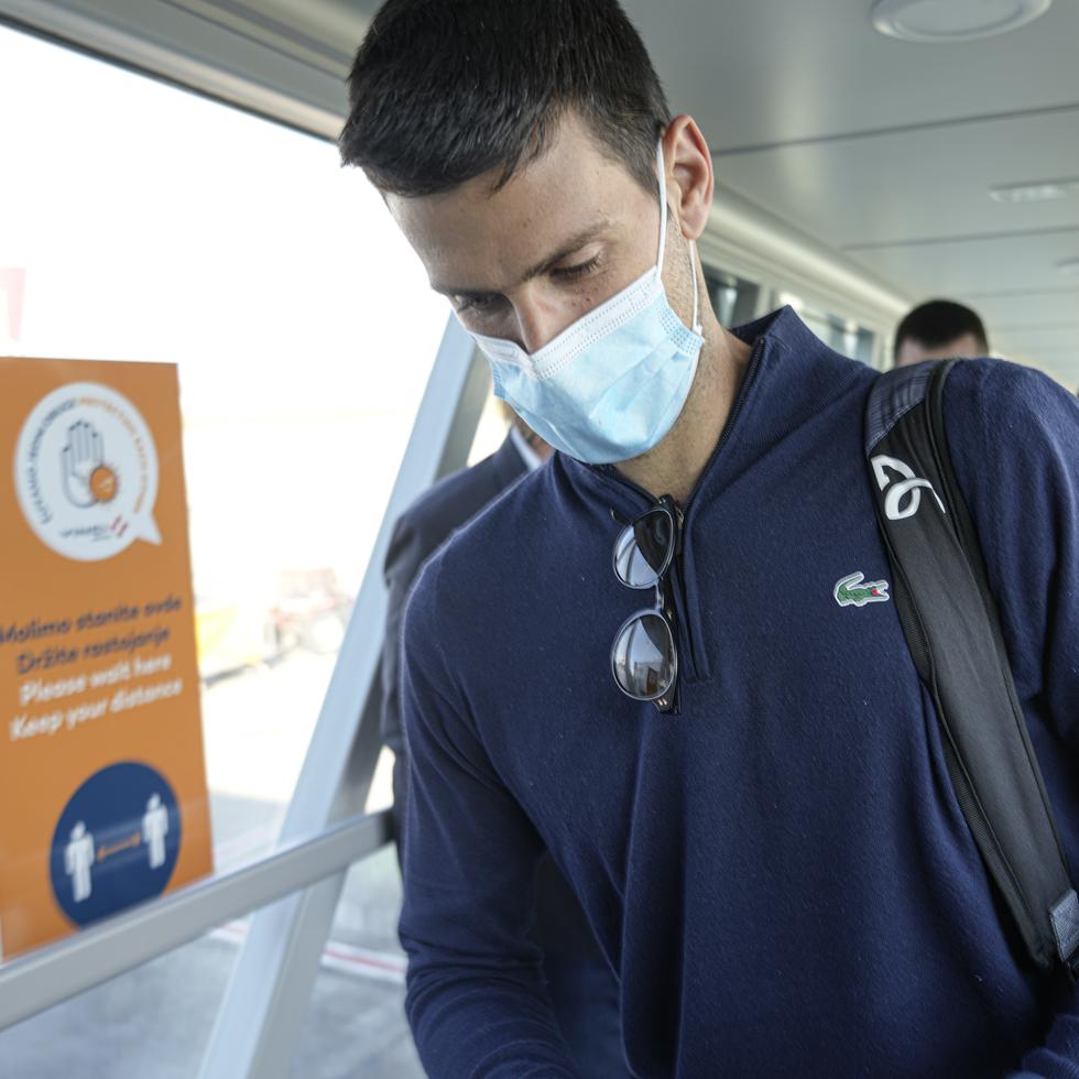 Novak Djokovic revisa sus documentos al arribar hoy al aeropuerto de Belgrado.