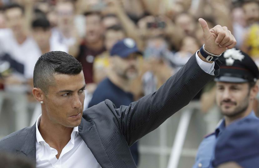 El astro portugués, Cristiano Ronaldo, saluda a sus aficionados mientras llega para someterse a los exámenes médicos en el estadio de la Juventus, en Turín, Italia. (AP)