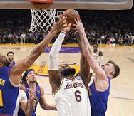 LeBron James (6), de los Lakers, intenta atrapar un rebote entre dos jugadores de los Nuggets de Denver, Bruce Brown y Christian Braun.
