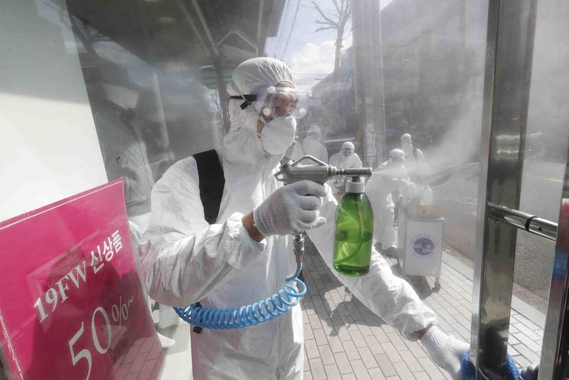 Un operario equipado con un equipo de protección rocía desinfectante en una estructura como medida de precaución contra el coronavirus, en una calle comercial de Seúl, Corea del Sur, el 27 de febrero de 2020. (AP/Ahn Young-joon)