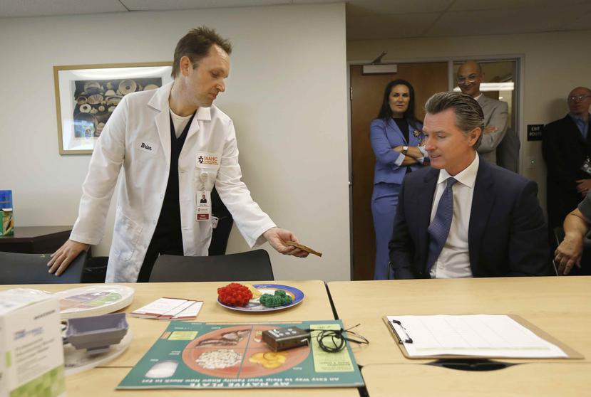 El gobernador de California, Gavin Newsom, conversa con el coordinador del Programa contra la Diabetes, Brian Shaw, a la izquierda, en el Centro Autóctono Estadounidense de Salud en Sacramento. (AP)