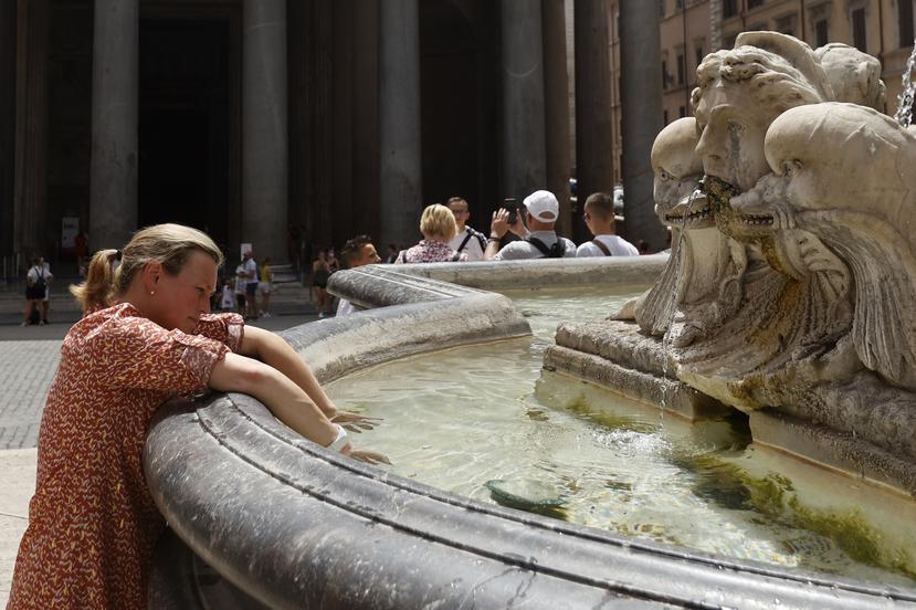 Una mujer se refresca en una fuente durante una ola de calor en Italia.