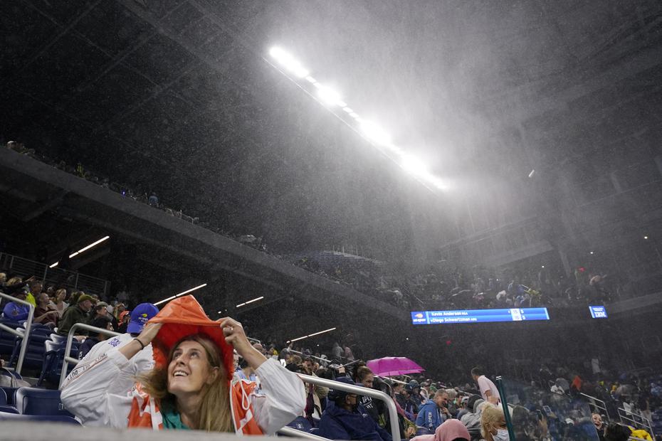 Una mujer se cubre de la lluvia en el estadio Louis Armstrong durante un partido en la segunda ronda del campeonato de tenis del US Open.