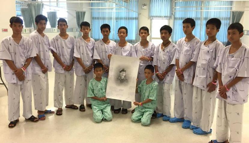 Los 13 miembros del equipo de fútbol rescatados sosteniendo un retrato del exmarine tailandés Saman Kunan (EFE).