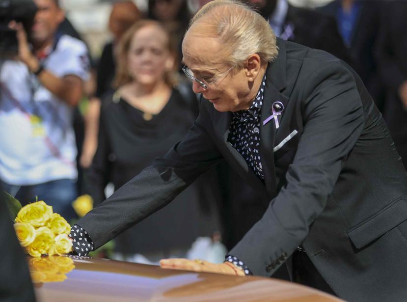 Willie Acosta, quien fue el asistente de Mercado por 50 años, pone una flor amarilla en el féretro.