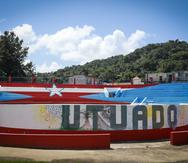 Una obra del artista Héctor Collazo, quien llevó su proyecto “78 pueblos y 1 bandera” al pueblo de Utuado. La pieza fue renovada recientemente por la líder comunitaria Ana Sofía Pomales y el agrónomo Raymond Rivera.