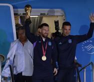 Lionel Messi de la selección argentina de fútbol saluda con el trofeo del Mundial de Fútbol Catar 2022 junto al seleccionador Lionel Scaloni a su llegada hoy, al Aeropuerto Internacional de Ezeiza a unos 22km de Buenos Aires (Argentina). EFE/ Raúl Martínez