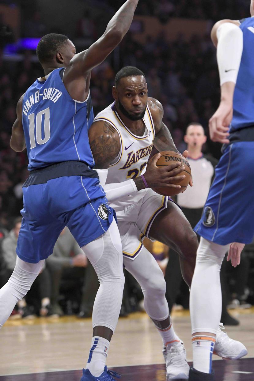 El base de los Lakers de Los Ángeles LeBron James ataca el aro contra la defensa del jugador de los Mavericks de Dallas Dorian Finney-Smith. (AP)