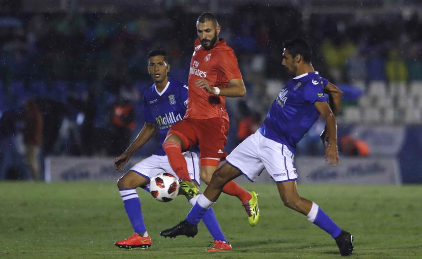 Karim Benzema (centro) intenta mantener el control del balón contra el Melilla. (AP)