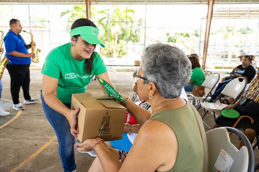 Una residente de la comunidad Las Ochenta recibe un obsequio de parte de una colaboradora del programa de servicio comunitario para empleados de MCS, Mindful Community Service.