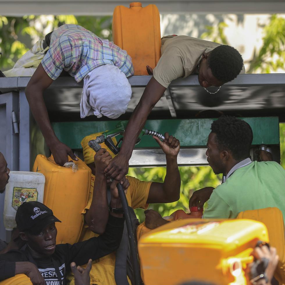 FILE - People wrangle over a gas pump as they try to get their tanks filled at a gas station, in Port-au-Prince, Haiti, Nov 4, 2021. The U.S. government is urging U.S. citizens to leave Haiti given the country’s deepening insecurity and a severe lack of fuel that has affected hospitals, schools and banks.  Gas stations remained closed on Thursday, Nov. 11, 2021, a day after the State Department issued its warning. (AP Photo/Odelyn Joseph, File)