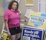 Jessica Porter, presidenta de comunicaciones del Partido Demócrata del condado de Shawnee, analiza un letrero en español que insta a los votantes a oponerse a una enmienda propuesta a la Constitución de Kansas para permitir que los legisladores restrinjan o prohíban aún más el aborto.