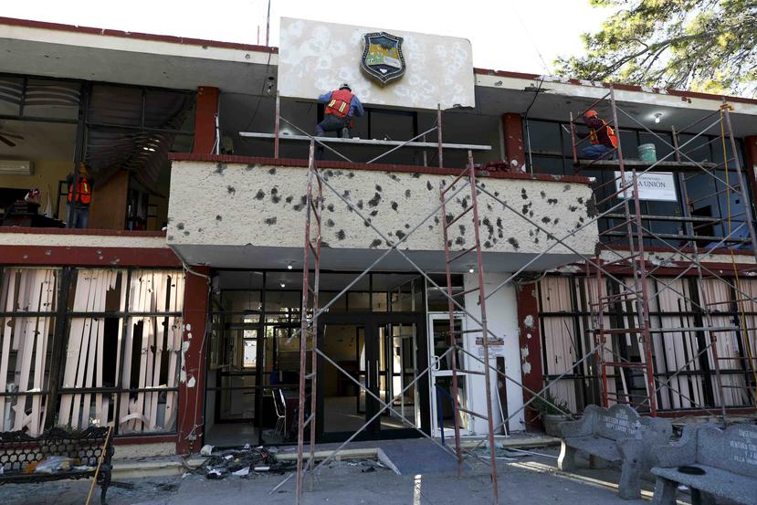 Trabajadores reparan la fachada del ayuntamiento, lleno de agujeros de bala, en Villa Unión, México. (AP Foto/Eduardo Verdugo)