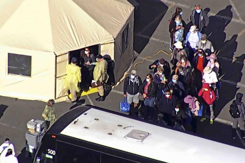 En esta imagen tomada de una transmisión de televisión se ve a los pasajeros del Grand Princess mientras esperaban por abordar unas guaguas en el puerto de Oakland. (AP)