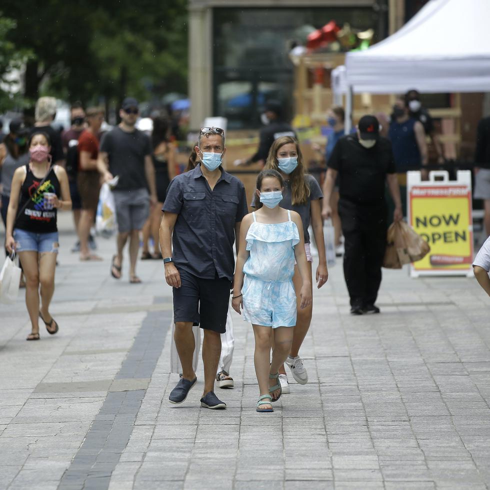 Pedestrians wear masks out of concern for the coronavirus, Sunday, June 28, 2020, while walking along a sidewalk, in Boston. (AP Photo/Steven Senne)