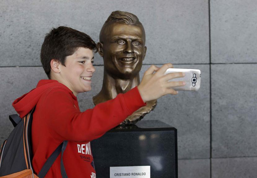 Un joven se toma una selfie con el peculiar busto de Cristiano Ronaldo. (AP)
