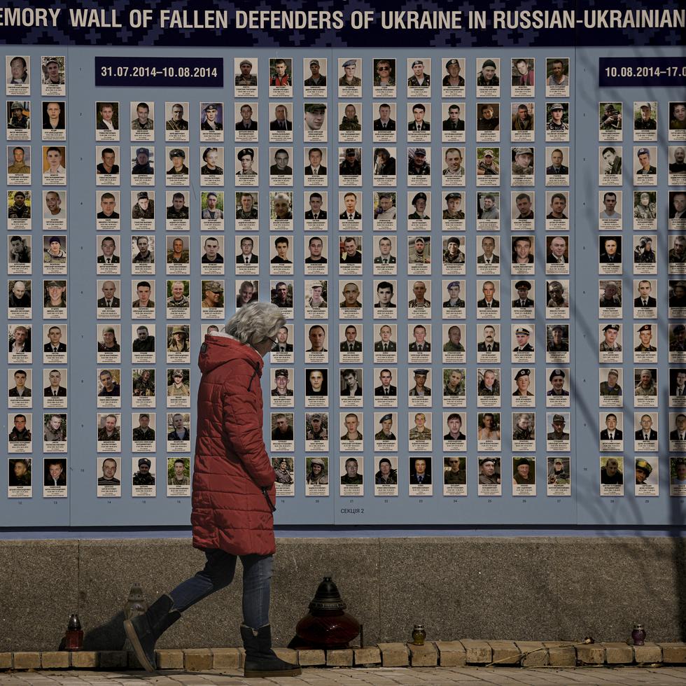 A woman walks by a memorial wall for those who lost their lives since the beginning of the conflict in Eastern Ukraine in Kyiv, Ukraine, Friday, March 18, 2022. Residents of the Ukrainian capital of Kyiv on took to a central square to arrange some 1.5 million tulips in the shape of the country's coat of arms, in a defiant show of normalcy as Russian forces surround and bomb the city. (AP Photo/Vadim Ghirda)