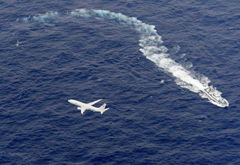 En esta imagen de archivo, tomada el 6 de diciembre de 2018, un barco de la guardia costera de Japón (arriba) y un avión militar estadounidense, vistos sobre el mar ante la costa de Kochi, al suroeste de Japón, durante una operación de búsqueda y rescate