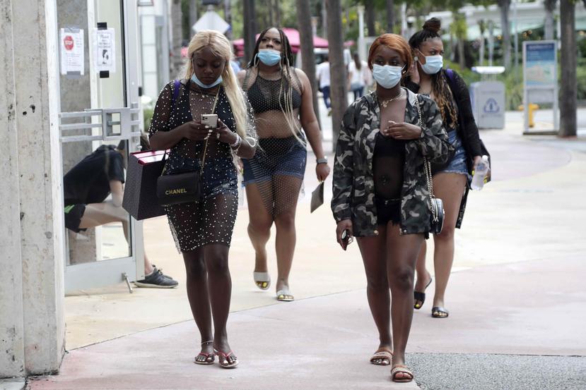Varias mujeres utilizan mascarillas mientras caminan por la avenidaLincoln, en Miami Beach. (AP)