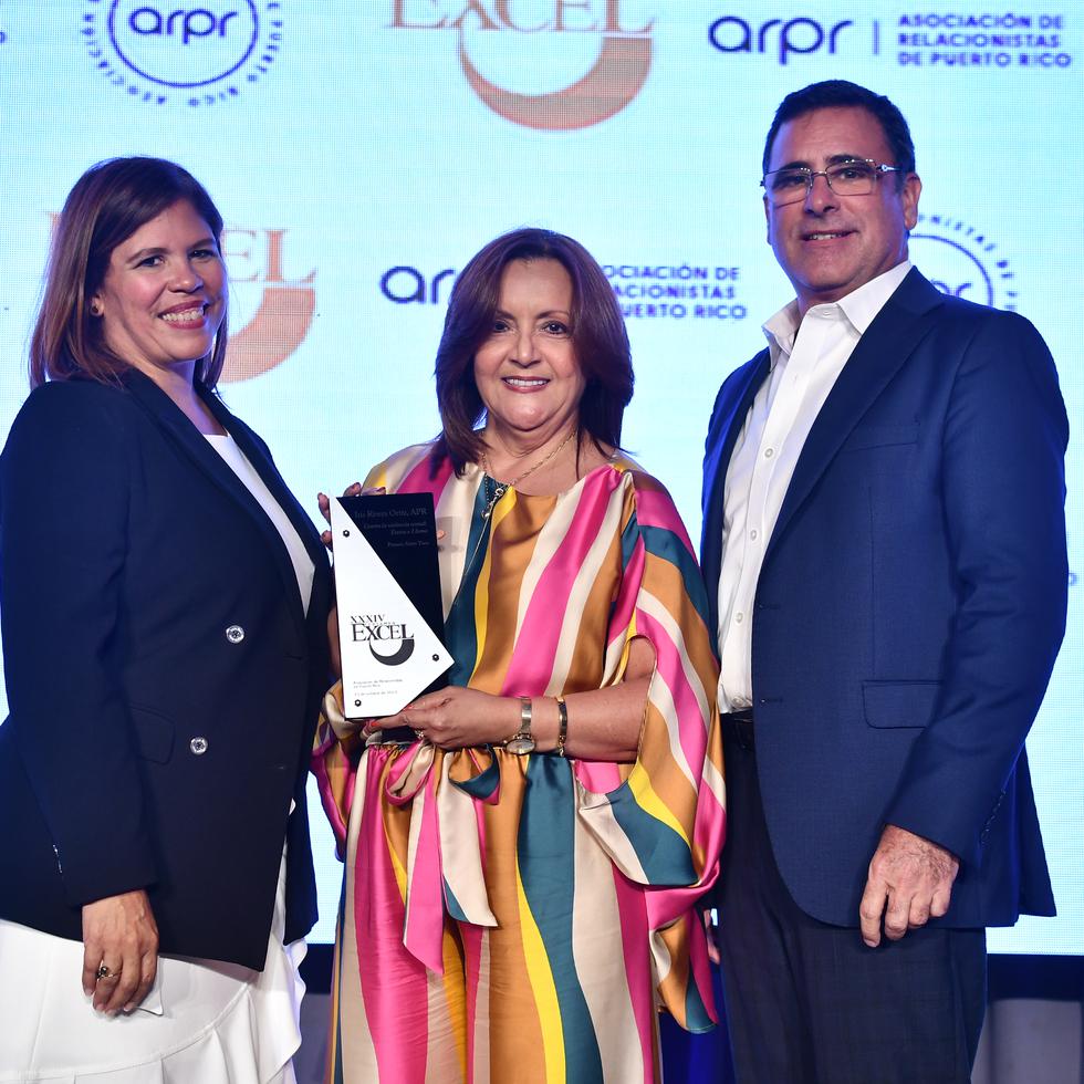 Iris Rivera, en el centro, recibe el Premio Sixto Toro por el trabajo "Contra la Violencia Sexual: Llama y Textea". A la izquierda, Raquel Rivera Torres, directora del jurado; y a la derecha Tomás Dardet, presidente de la ARPR.