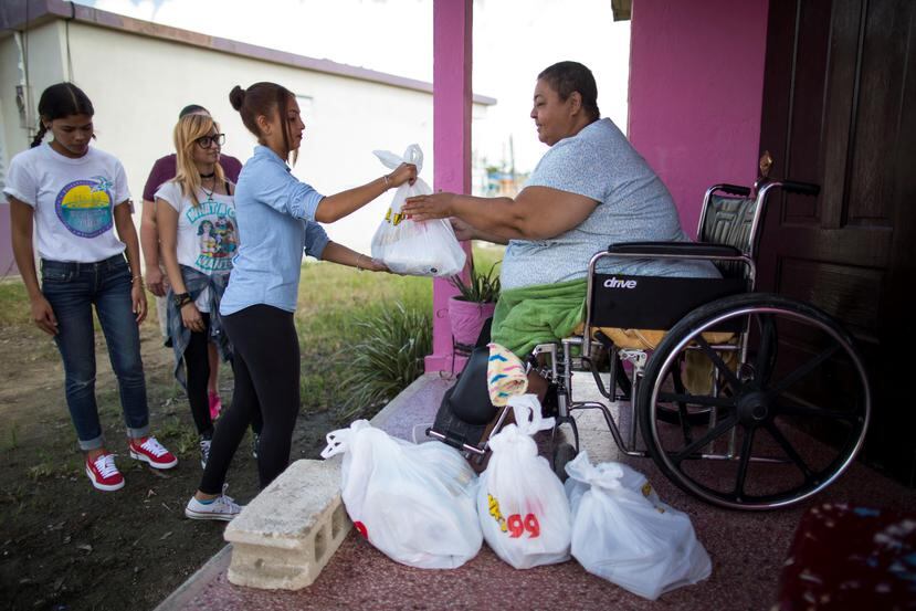 Voluntarios y personal de la organización P.E.C.E.S. le entregan suministros de primera necesidad a una vecina de la calle Del Fuego, en Punta Santiago, Humacao. (Archivo / GFR Media)