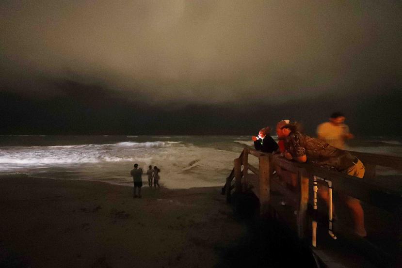 Varias personas en la playa Vero observan el nivel del mar ante el impacto del huracán Dorian. (AP)