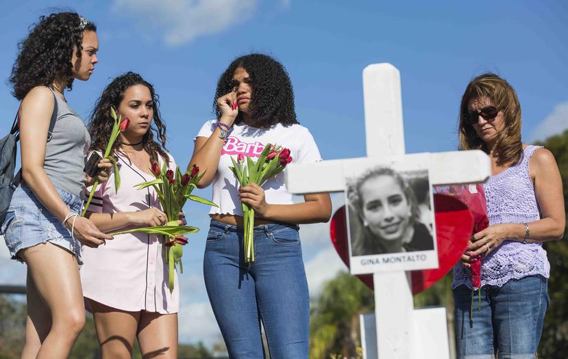 Varias estudiantes colocan flores a una cruz en honor a una de las estudiantes fallecidas en el tiroteo reportado el pasado miércoles. (AP)