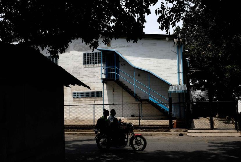 Una pareja de motociclistas pasan por la entrada de una fábrica donde policías de Aragua ejecutaron a cuatro hombres. (AP)