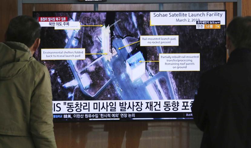 Dos personas observan una pantalla que muestra una imagen del Centro de Lanzamiento de Satélites Sohae, en Tongchang-ri, Corea del Norte. (AP)