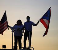 El candidato a la gobernación por el Partido Nuevo Progresista, Pedro Pierluisi, sujeta la bandera de Puerto Rico mientras que su compañera de papeleta, Jenniffer González, candidata a comisionada residente, sostiene la de Estados Unidos.