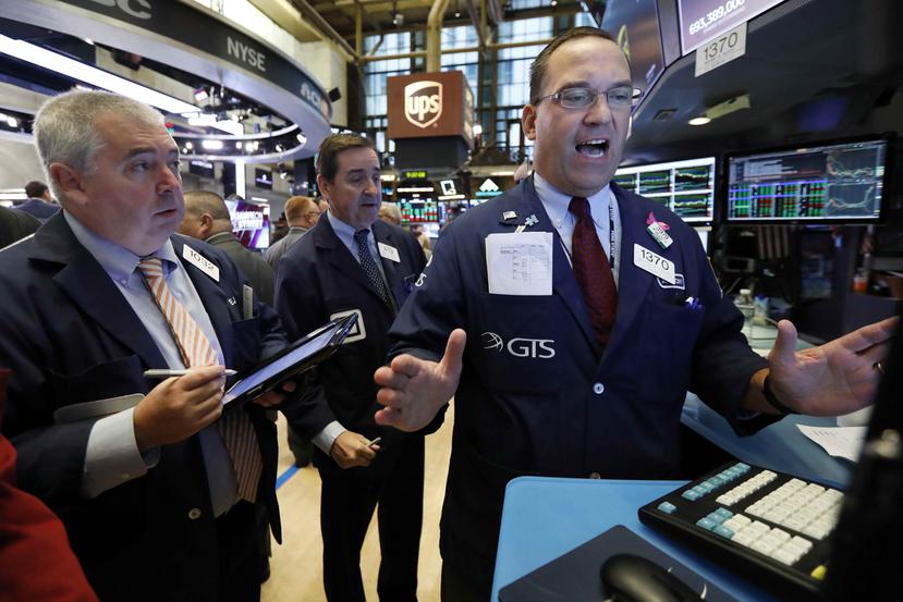 Trabajadores del New York Stock Exchange discuten una movida financiera. (AP)