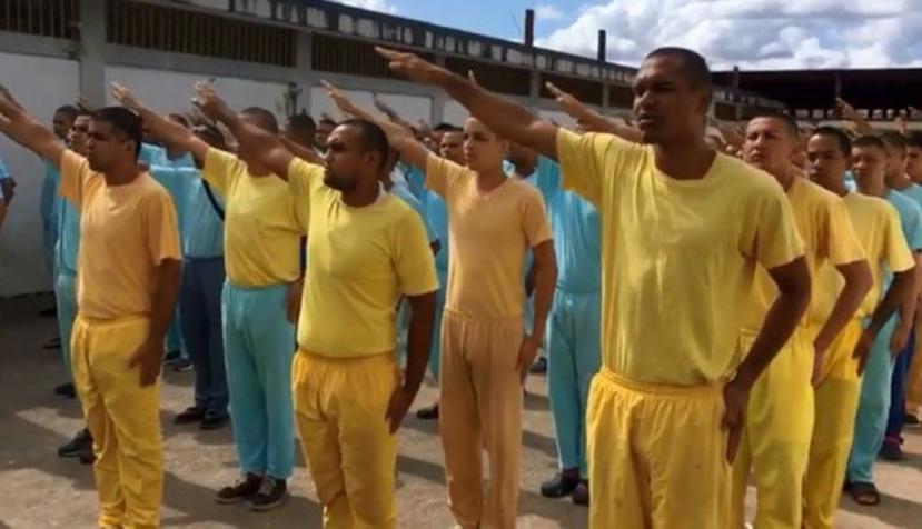 Como se ve en las imágenes difundidas en Facebook, los internos permanecen uniformados de azul o amarillo, alineados en una formación militar y coreando lo que se les ordena (Captura / Video Facebook).