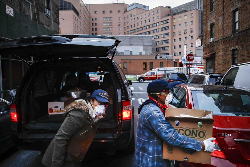 Sandra Pérez (izquierda) y Francisco Ramírez entregan una donación de comestibles a un hombre que lo necesita en Queens, Nueva York. (AP)