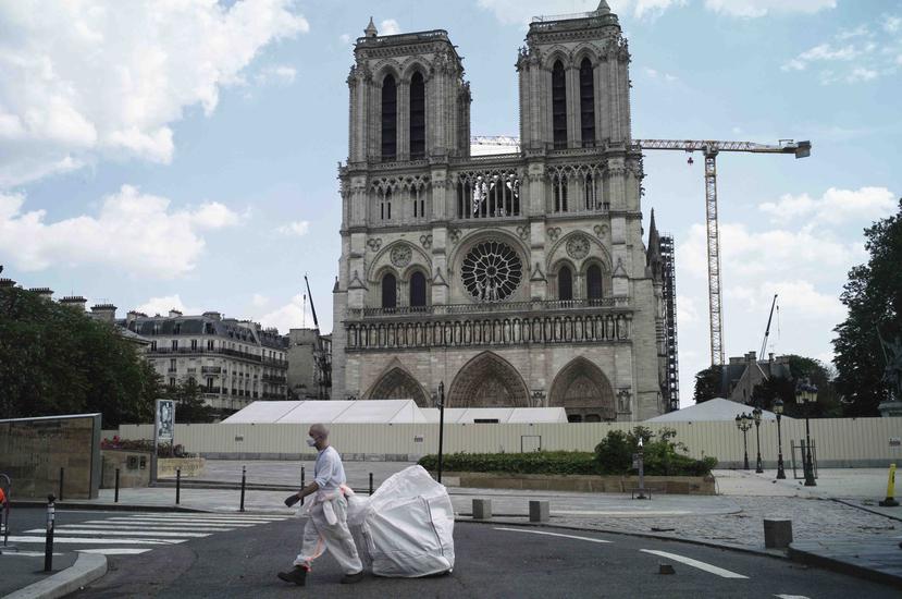 Un hombre con mascarilla limpia los alrededores de la Catedral de Notre Dame. (AP)