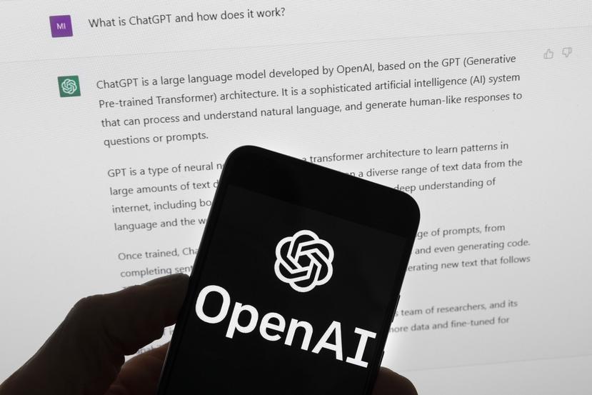 El logotipo de OpenAI se ve en un teléfono móvil frente a la pantalla de una computadora que muestra el ChatGPT.
