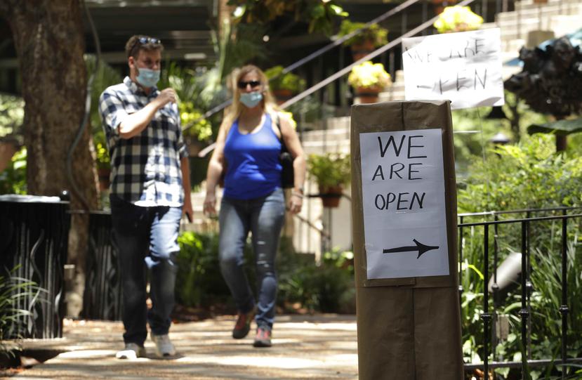 Unas personas con mascarillas caminan frente a un negocio que reabrió en San Antonio, Texas, el jueves 14 de mayo de 2020, luego de que las autoridades del estado redujeron las medidas implementadas por la pandemia de coronavirus. (AP/Eric Gay)