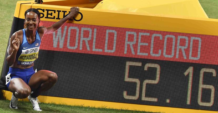 La estadounidense posa con el reloj que muestra su récord mundial de los 400 metros con vallas femeninos en el Mundial de atletismo. (AP/Martin Meissner)