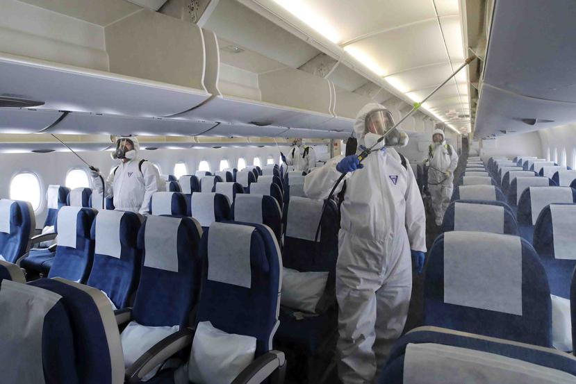 Trabajadores con trajes protectores rocían desinfectante dentro de un avión con destino a Nueva York como medida de precaución contra el nuevo coronavirus, en el Aeropuerto Internacional de Incheon, Corea del Sur, el miércoles 4 de marzo de 2020. (Suh Myo