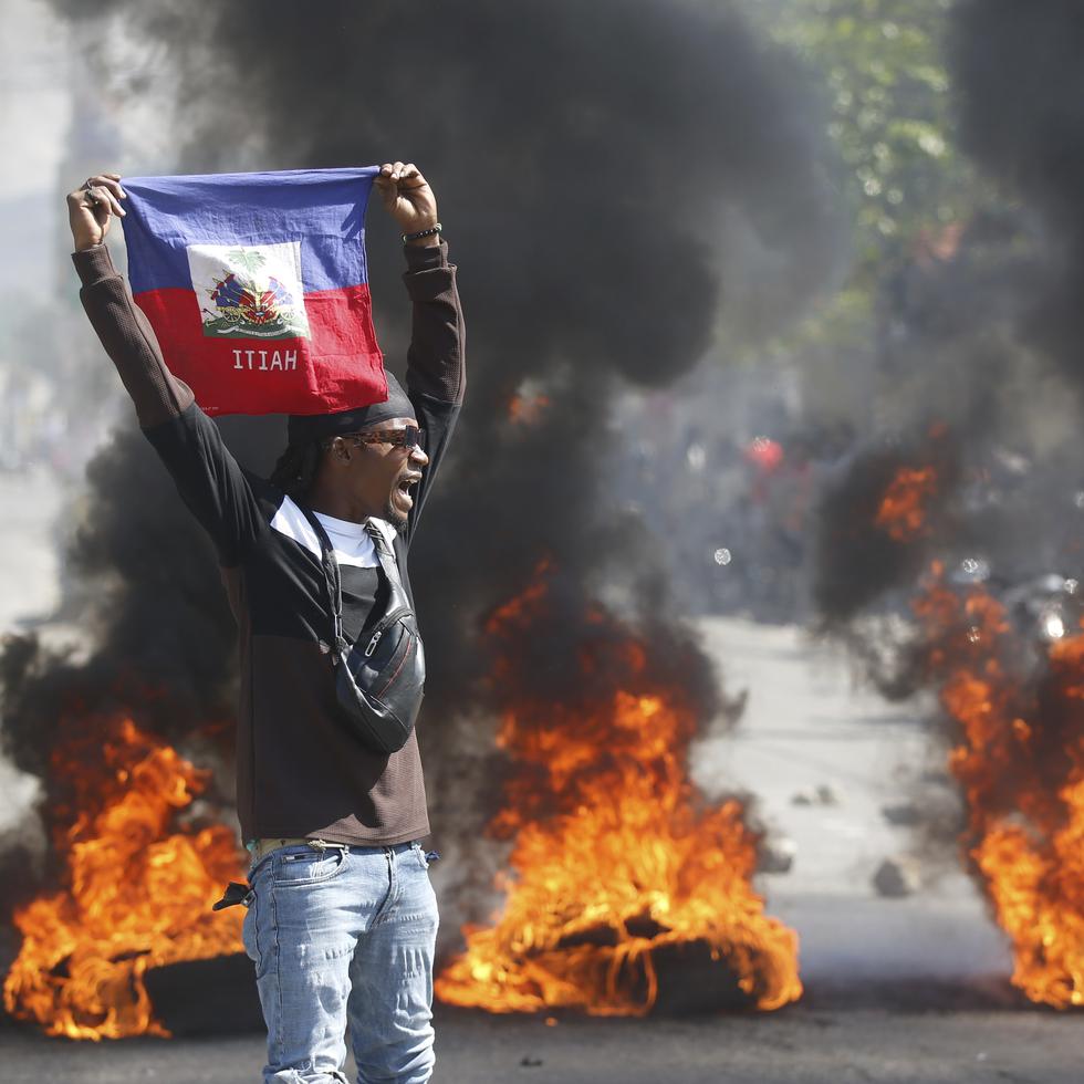 Un manifestante muestra una bandera haitiana durante una protesta para exigir la renuncia del primer ministro del país, Ariel Henry, en Puerto Príncipe, Haití, el 1 de marzo de 2024. (AP Foto/Odelyn Joseph)