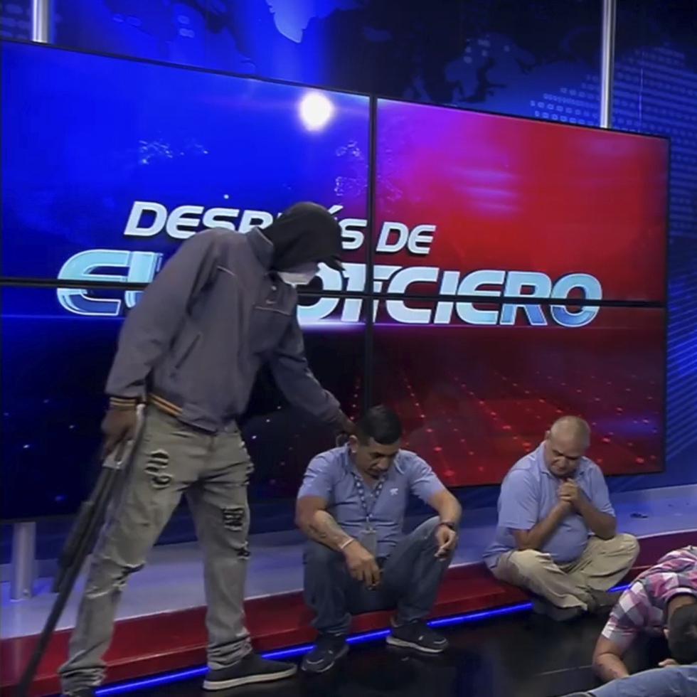 Imagen extraída del vídeo emitido por el canal TC Televisión en el que aparece un hombre encapuchado y armado al lado de dos trabajadores del medio en plena retransmisión en vivo, en Guayaquil, Ecuador, el martes 9 de enero de 2024.