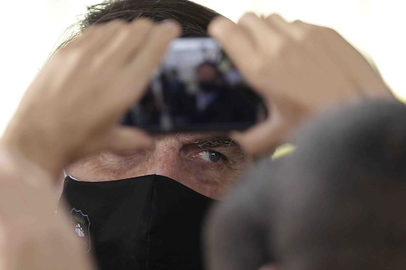 El presidente de Brasil, Jair Bolsonaro, sale con una máscara facial en medio de la nueva pandemia de coronavirus. (AP)