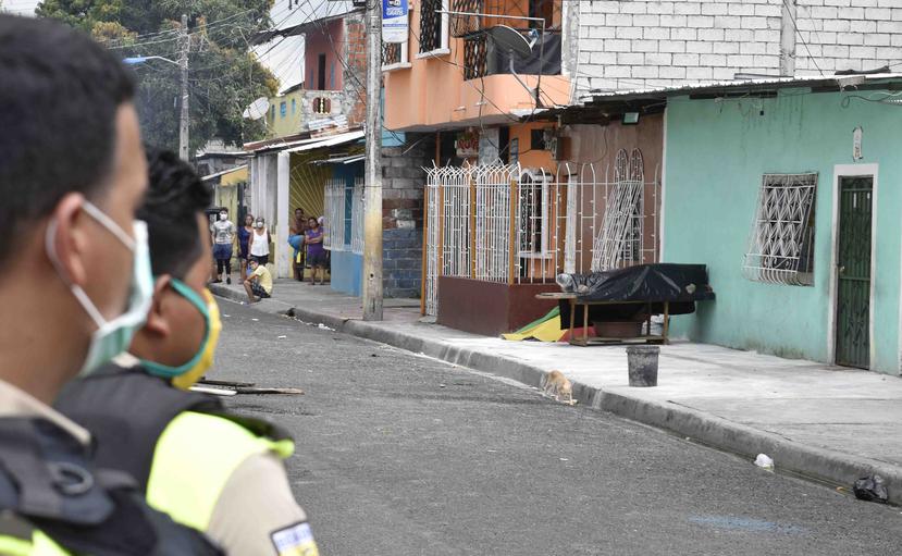 Oficiales observan un cadáver ubicado en las afueras de un hogar en un suburbio de Guayaquil, Ecuador. (AP)