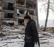 Una mujer pasa frente a un edificio dañado por los bombardeos rusos, el 13 de marzo de 2022, en Kharkiv, Ucrania.